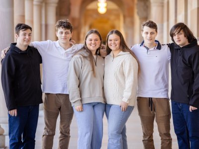 a group of six people stand in a corridor with their arms around each other